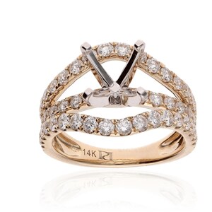 Op de afbeelding: Een gouden verlovingsring met een split-schachtontwerp, met een centrale zetting en meerdere rijen kleine, sprankelende diamanten. De ring is gemarkeerd met "14K" en een merkteken.