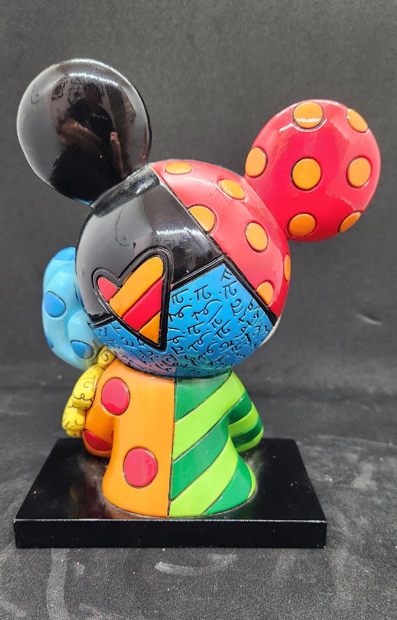 K&ouml;nnte beinhalten: Eine farbenfrohe, vielseitige Figur von Mickey Mouse. Die Figur ist aus bemaltem Harz gefertigt und hat ein Farbschema in Schwarz, Rot, Gelb, Blau, Gr&uuml;n und Orange. Die Figur steht auf einem schwarzen Sockel.