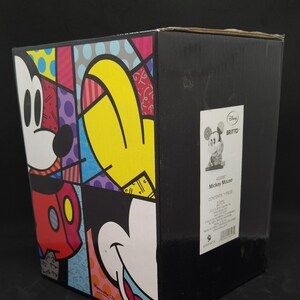 K&ouml;nnte beinhalten: Eine farbenfrohe Mickey Mouse Figur im Pop-Art-Stil in einer schwarzen Box. Die Box hat ein Etikett mit den Disney- und Britto-Logos und dem Text "Mickey Mouse".