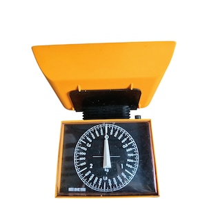 May include: A vintage orange and black kitchen scale. The scale features a circular dial with measurements in kilograms. The base is rectangular with a black face and white numbers. The top is a bright orange bowl. The brand name "EKS" is visible.