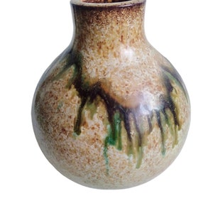 May include: A round, ceramic vase with a textured, speckled surface in shades of brown, green, and white. The vase has a wide, round base and a narrow neck.