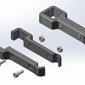 May include: Two black plastic brackets with holes for screws and nuts. The brackets are designed to be attached to a surface and have a slot for a rod or pipe to be inserted.