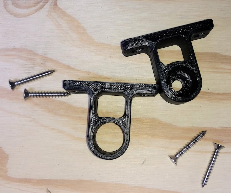 May include: Two black plastic wall mounts with a circular hole in the center. The mounts are designed to hold a shelf or other object. Four silver screws are included.