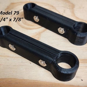 May include: Two black plastic pipe clamps, each with a 3/4 inch inner diameter and a 7/8 inch outer diameter. The clamps are designed to connect two pipes together.