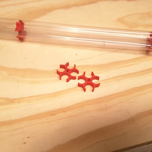 May include: Two red plastic bullet feeders for a reloading press. The feeders are designed to hold bullets in place while they are being loaded into a cartridge.