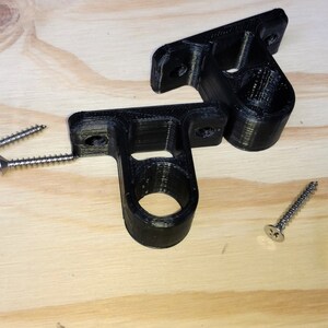 May include: Two black plastic wall mounts with a round hole in the center. Four silver screws are included.