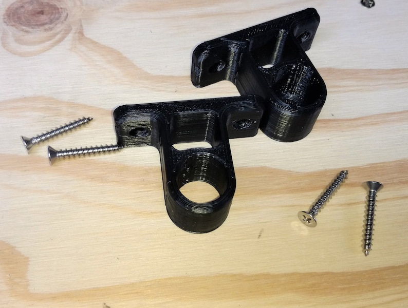 May include: Two black plastic wall mounts with a round hole in the center. Four silver screws are included.
