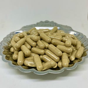 Puede incluir: Primer plano de un montón de cápsulas beige en un plato plateado con forma de concha.