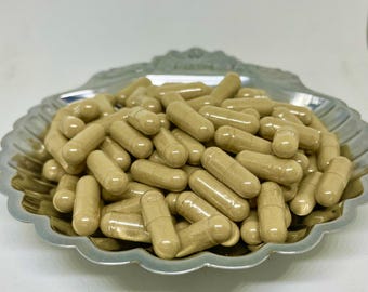 May include: A close-up of a pile of beige capsules in a silver shell-shaped dish.
