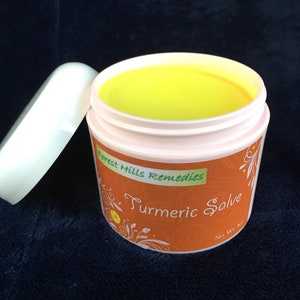 K&ouml;nnte beinhalten: Ein kleines, wei&szlig;es Glas mit einem gelben Deckel. Das Glas enth&auml;lt eine gelbe Salbe und tr&auml;gt ein Etikett mit der Aufschrift "Forest Hills Remedies Turmeric Salve Net Wt 4 oz."