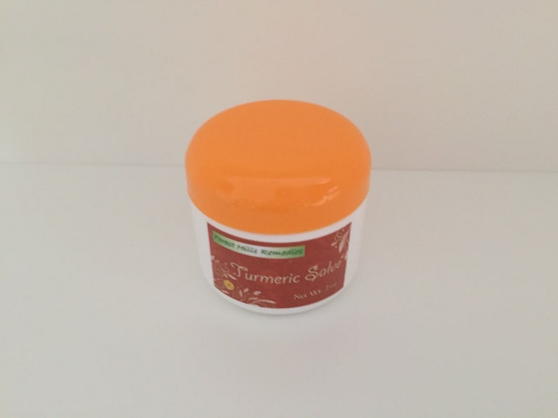 K&ouml;nnte beinhalten: Ein wei&szlig;es Glas mit einem orangenen Deckel. Das Glas ist mit "Turmeric Salve" beschriftet, &uuml;ber dem Etikett steht "Forest Hills Remedies".