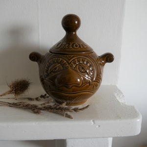 May include: A brown ceramic onion jar with a face and the word "Onion" on the lid.