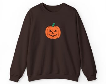 May include: A dark brown sweatshirt featuring an embroidered orange jack-o'-lantern with a green stem. The pumpkin has a carved face with triangular eyes and a toothy grin. The long-sleeved top is a casual garment for Halloween.