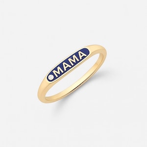 May include: A gold ring featuring the word "MAMA" in white lettering on a navy blue enamel panel. A small, clear gemstone is set near the word "MAMA". The ring has a simple band design.