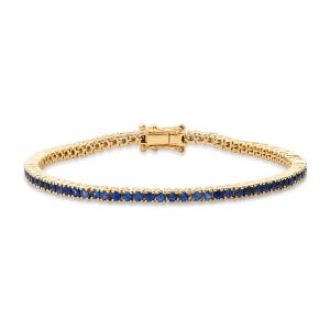 May include: A gold tennis bracelet with a row of blue sapphires.