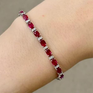 Può includere: Un braccialetto tennis in oro bianco con rubini rossi ovali e diamanti rotondi.