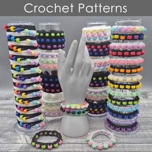 May include: A collection of colourful crocheted bracelets with different patterns, including hearts, squares, and stripes. The bracelets are displayed on stands and a hand model. The text "Crochet Patterns" and "Instant Digital Download" is visible in the image.