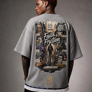 Pode incluir: Uma t-shirt cinzenta de manga curta em tecido canelado texturizado. As costas apresentam uma grande impressão gráfica com o texto Faith + Friction, rodeado por painéis mais pequenos de texto e imagens, e uma bainha com franjas brancas.