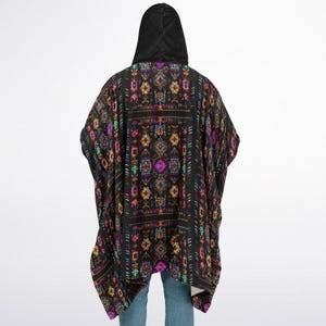 May include: Black hooded poncho with a colorful geometric pattern. The poncho has a black hood and is made of a soft, comfortable fabric.