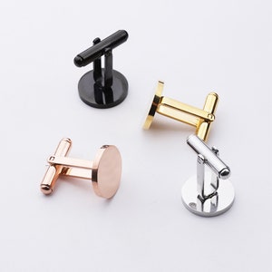 May include: Four cufflinks in different finishes: black, gold, silver, and rose gold. Each cufflink has a round, smooth surface.