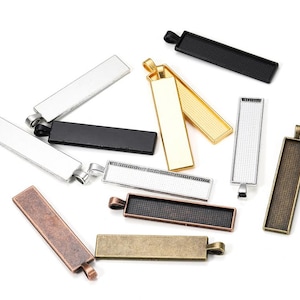 Könnte beinhalten: Sortiment von 10 rechteckigen Metall-Anhänger-Tabletts in verschiedenen Größen und Ausführungen, darunter Silber, Gold, Schwarz, Bronze und Kupfer. Die Tabletts haben eine glatte, polierte Oberfläche und sind für die Verwendung mit Harz, Epoxidharz oder anderen Bastelmaterialien konzipiert.