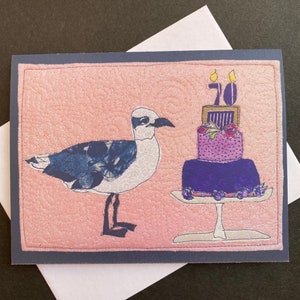 Carte du 70e anniversaire, mouette avec gâteau et message. Carte pliée imprimée à partir de techniques mixtes originales. Grande carte d'anniversaire pour les amoureux de la plage.