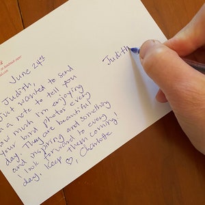 May include: A handwritten note on white paper with blue ink. The text includes the name "Judith" and a message about enjoying bird photos. The date "June 24th" is also visible. The note is being written with a blue pen.