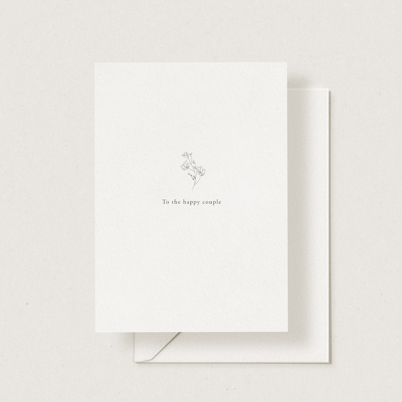 May include: A simple white card with a small black line drawing of a flower and the text "To the happy couple".