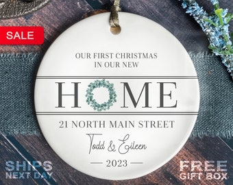 May include: White ceramic Christmas ornament with the text "Our first Christmas in our new home" and a wreath design. The address "21 North Main Street" and the names "Todd & Eileen" are also included, along with the year "2023".
