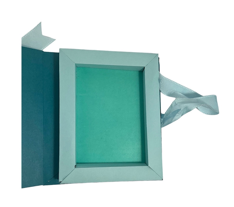 Op de afbeelding: Een lichtblauwe cadeaudoos met een lichtblauw lint. De doos is open en de binnenkant is bekleed met lichtgroen papier.
