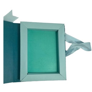 Op de afbeelding: Een lichtblauwe cadeaudoos met een lichtblauw lint. De doos is open en de binnenkant is bekleed met lichtgroen papier.