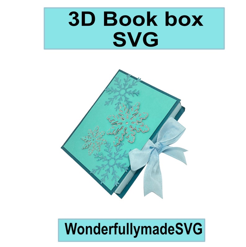 Op de afbeelding: Een tealblauwe 3D-boekendoos met een blauwe strik en sneeuwvlokkenuitsnijdingen. De doos is onderaan gelabeld met "WonderfullymadeSVG".