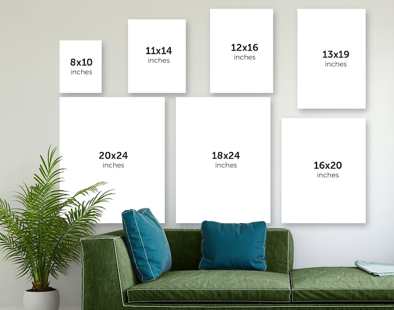 May include: A white wall with nine different sized white frames, each with black text indicating the size of the frame in inches. The frames are arranged in a grid pattern. The frames are hanging on a white wall. There is a green couch in the foreground with two blue throw pillows.