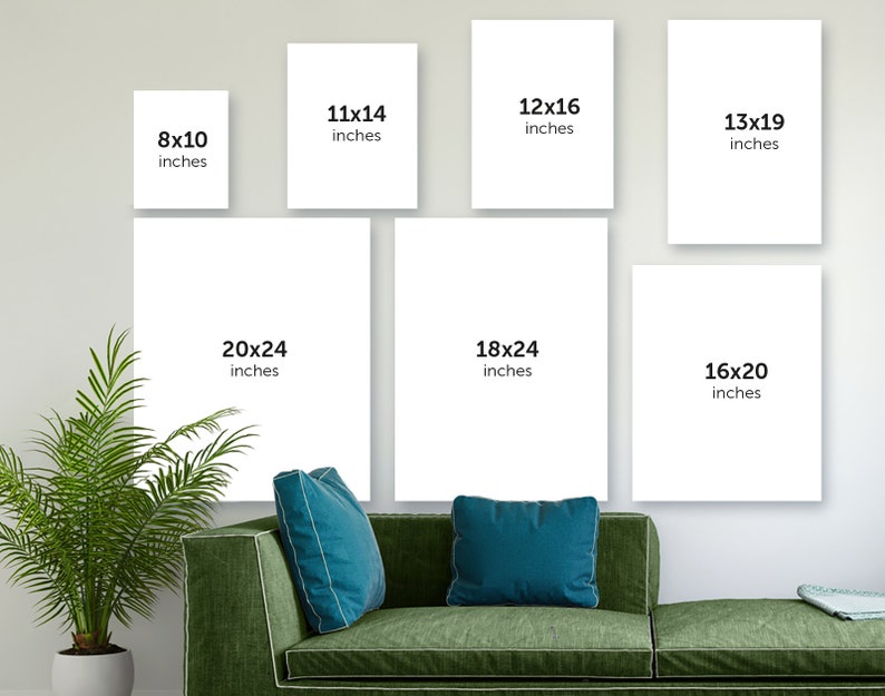 May include: A white wall with nine different sized white frames with black text indicating the size of each frame in inches. The frames are arranged in a grid pattern. The frames are hanging on a white wall. A green sofa with two blue cushions is in the foreground.