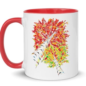 K&ouml;nnte beinhalten: Wei&szlig;e Keramiktasse mit rotem Rand und Henkel. Die Tasse zeigt eine farbenfrohe Illustration eines Birkenbaums mit roten, orangen, gelben und gr&uuml;nen Bl&auml;ttern.