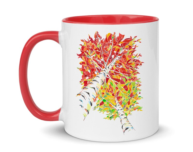K&ouml;nnte beinhalten: Wei&szlig;e Keramiktasse mit rotem Rand und Henkel. Die Tasse zeigt eine farbenfrohe Illustration eines Birkenbaums mit roten, orangen, gelben und gr&uuml;nen Bl&auml;ttern.