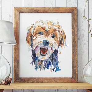May include: A framed print of a dog's face, created with a mosaic of colourful paper pieces. The dog is a small, fluffy breed with brown, white, and black fur. The dog is smiling with its tongue slightly sticking out.
