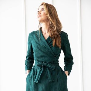 May include: A long-sleeved, emerald green wrap dress with a tie belt. The dress is made of a linen fabric and has a relaxed fit.