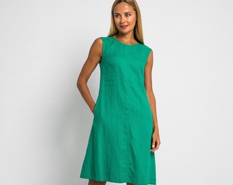 May include: A sleeveless, emerald green linen dress with a straight neckline and pockets. The dress has a slightly flared skirt and is knee-length.