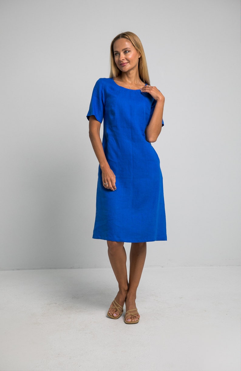 May include: A royal blue linen dress with a scoop neck and short sleeves. The dress is knee-length and has a straight silhouette.