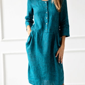 May include: A teal linen dress with a button-up front and pockets. The dress has a relaxed fit and a midi length.