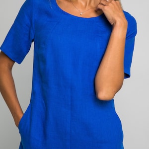 May include: A royal blue linen dress with short sleeves and a scoop neck. The dress has two pockets on the front.