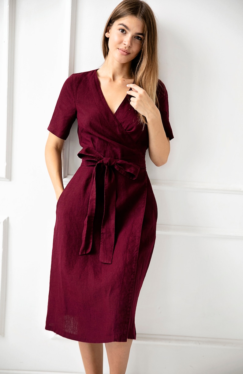 May include: A burgundy linen wrap dress with a V-neckline and a tie belt.