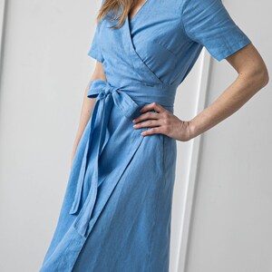 May include: A light blue linen wrap dress with short sleeves and a tie belt.