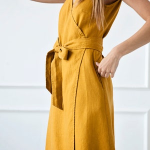 May include: A mustard yellow linen wrap dress with a V-neckline and a self-tie belt.