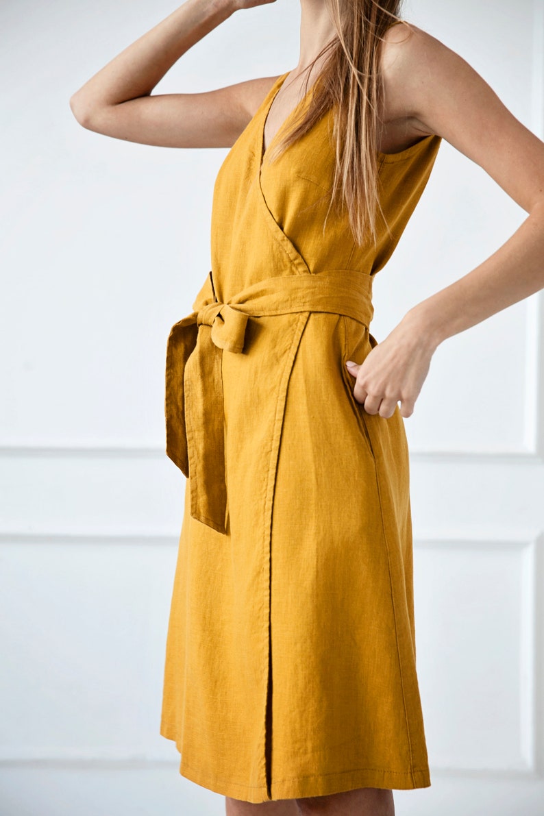 May include: A mustard yellow linen wrap dress with a V-neckline and a self-tie belt.