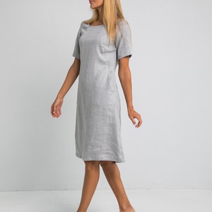 May include: A gray linen dress with short sleeves and a scoop neck. The dress is knee-length and has a relaxed fit.