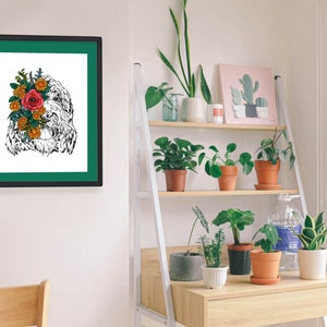 May include: A black and white illustration of a dog with a bouquet of flowers covering its face. The illustration is framed in a black frame with a green mat. The frame is hanging on a white wall.
