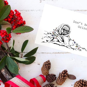 May include: A black and white illustration of a dog wrapped in Christmas lights with the text "Don't be a Grinch."