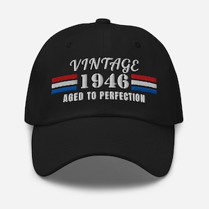 May include: Black baseball cap with embroidered text "VINTAGE 1946 AGED TO PERFECTION". The text is in white, with red, white, and blue stripes. A classic, adjustable hat.